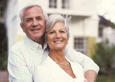 Senior Couple posing for image in front of house